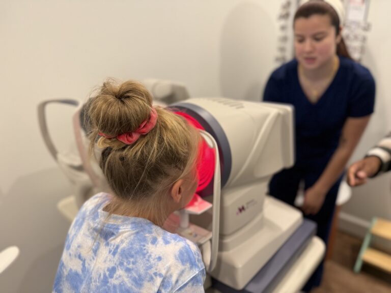 Navigation Eye Care staff member assisting a young girl with retinal imaging scan in Chesapeake VA