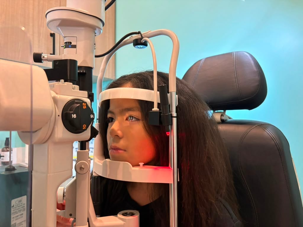 A young patient rests her chin on a slit lamp during an eye exam at Navigation Eye Care, Chesapeake VA