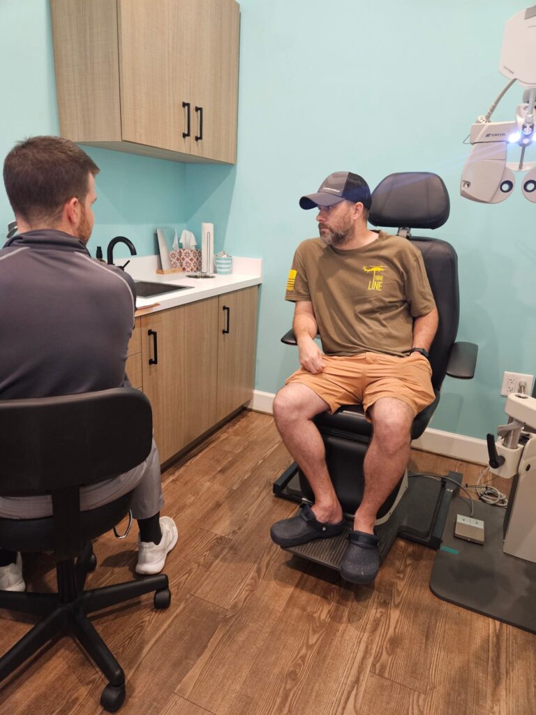 A patient sits in the exam chair speaking with an eye doctor during a consultation at Navigation Eye Care.