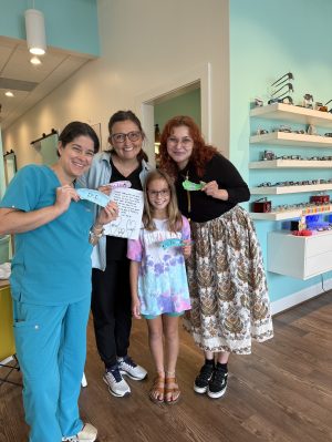 Navigation Eye Care team celebrating with a young patient at the Chesapeake VA eye care clinic