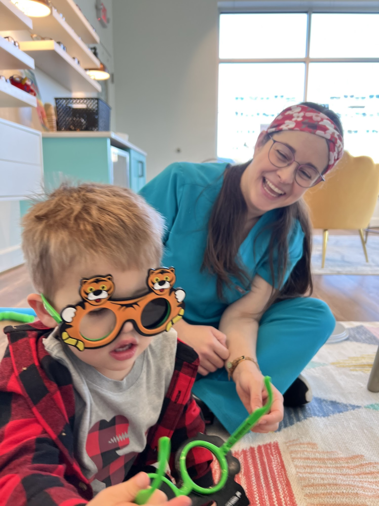Navigation Eye Care team member with child wearing fun novelty glasses during visit at Chesapeake VA eye care practice