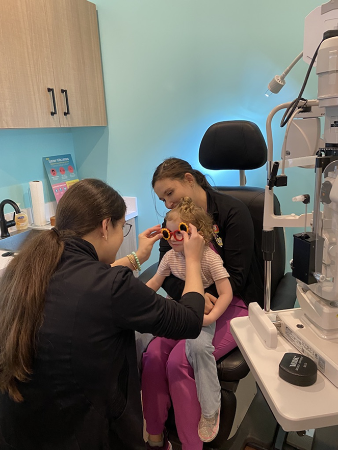 Dr. Amber Teten fitting trial frames on a young toddler during pediatric eye exam at Navigation Eye Care Chesapeake VA